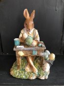 Kanin sitter vid skrivbord och målar ägg